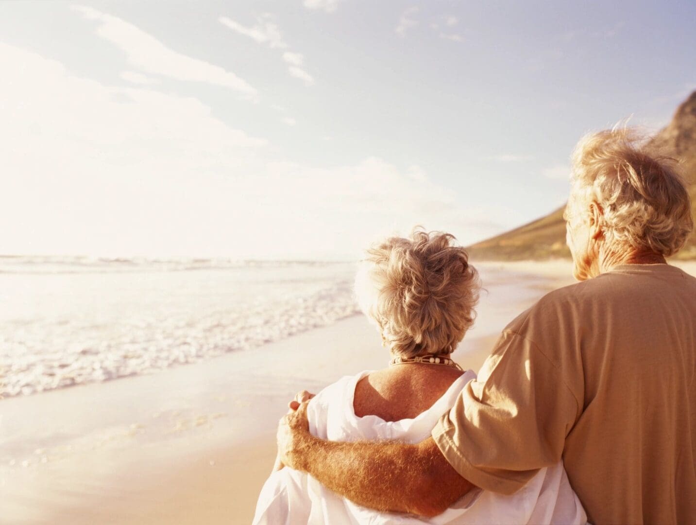 A man and woman hugging on the beach.